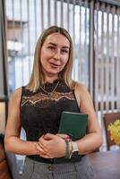 Woman Notebook Professionalism. Blonde woman holds notebook indoors, modern office, day, posing for professional portrait. photo
