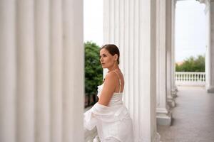 Woman Columns Balcony. Lady in white looks outward from a columned balcony during daytime. photo