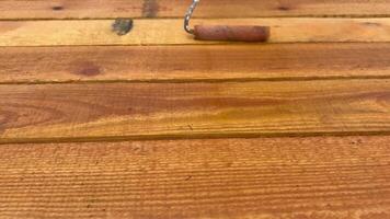 Treating wood with a protective solution using a hand roller. Hands in protective gloves cover the wood with a protective solution. video