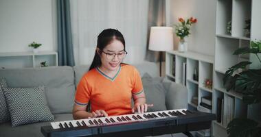 Medium shot, Young woman is relaxing and enjoying playing music on an electronic keyboard in a quiet house. Leisure activities at home video