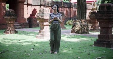 Handheld shot, Relaxed Asian woman listening to music on wireless headphones over a mobile app while walking leisurely in a quiet place. video