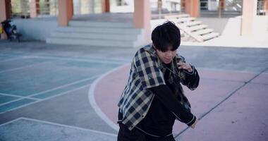 Handheld high angle view shot, Young Asian man dances with energy and cool moves in an outdoor multipurpose pavilion. Enjoy the rhythm and creativity. Solo dance. video