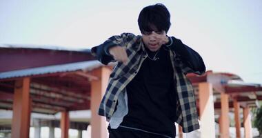 Handheld steady shot, Young Asian man dances with energy and cool moves in an outdoor multipurpose pavilion. Enjoy the rhythm and creativity. Solo dance. video