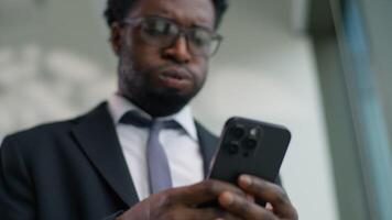 Upset African American male guy businessman business man in office looking smartphone reading bad news worried with mobile phone frustrated stressed disappointed sad financial failure digital error video