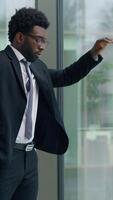 Thinking problem solution African American business man looking window in office decide trouble work job failure tired businessman hard difficult decision leaning on glass think male hesitate puzzled video