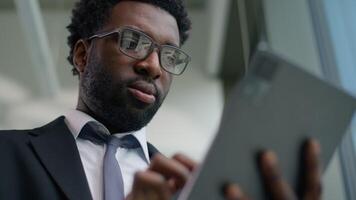 Happy African American businessman in office smiling using digital tablet modern technology business man smiling success professional male manager corporate entrepreneur innovation working internet video