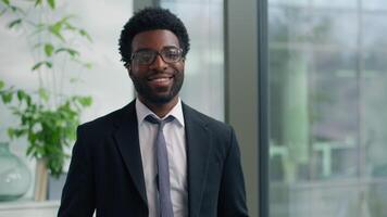 African American man business guy male businessman looking in window think gazing look at camera smiling happy portrait job ambition professional worker indoors smile work success ethnic entrepreneur video
