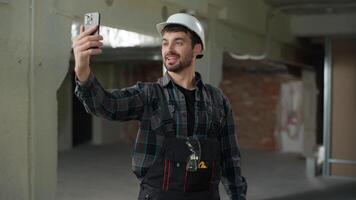 Construction engineer man builder Caucasian guy male talk call mobile phone conference chat on building site handyman foreman architect talking smartphone friendly smiling apartment renovation video