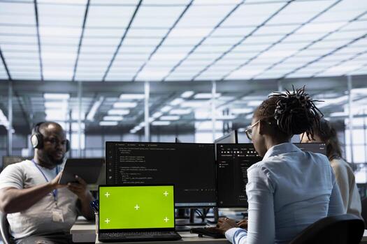 Green screen laptop in data center in front of IT support specialists working together, supervising server rows. Employees overseeing supercomputers using mockup notebook device photo