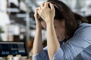 Young employee deals with emotional strain and frustration of business failure, disappointment and challenges. Woman going through a crisis to find solutions for professional struggle. photo
