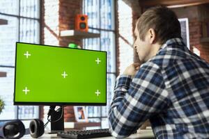 Employee completing spreadsheets on chroma key computer, entering numerical data into cells, calculating totals. Man analyzing figures on isolated screen PC monitor, using spreadsheet software photo