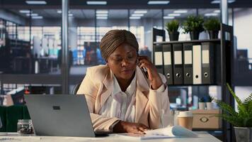 African american entrepreneur works on financial planning on her mobile phone, answering a call from investors to share insight and data. Woman CEO does business tasks on phone call. Camera A. photo