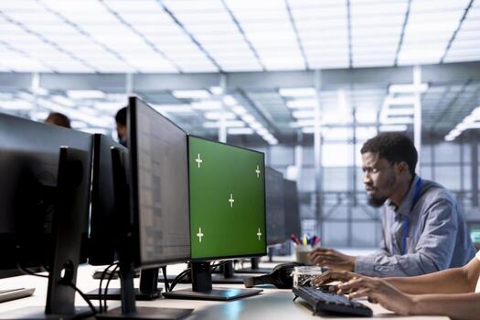 Programmer in data center updates rigs systems on green screen PC to protect servers from exploitable software vulnerabilities. IT expert using chroma key computer to look for errors affecting servers photo