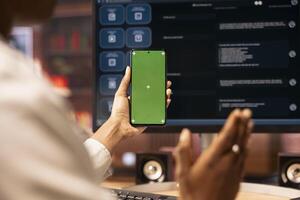 Woman using isolated screen smartphone and AI LLM chatbot on computer display in apartment office. Close up of person holding mockup phone uses artificial intelligence chatbot on monitor photo
