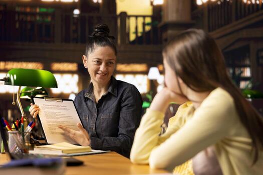 Woman tutor mentoring elementary scholars on a team project, presenting a file to help and guide them towards assignment success, Effective study techniques during private lessons. photo