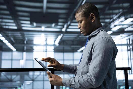 Engineer in data center with tablet integrating AI driven automation tools, running predictive maintenance routines. Man ensuring continuous uptime of server room, managing data flows photo