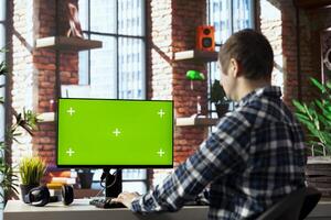 Man in home office using mockup computer, preparing presentation slides, adjusting layouts. Employee finishing company project, writing summaries, saving files on green screen PC, uploading materials photo