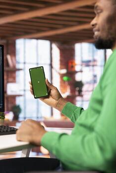 Happy man at home using green screen phone to browse social media website, looking at memes. Jolly person in apartment looking at funny content online on chroma key smartphone photo