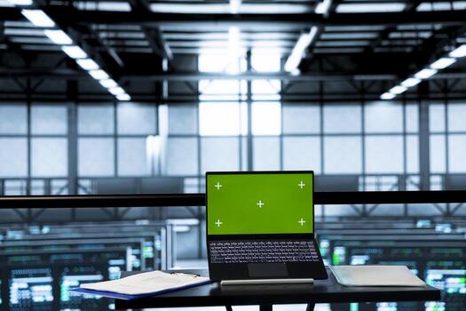 Green screen mockup laptop in empty data center used to run security patches. Isolated screen chroma key notebook device in server room with nobody in used for overseeing infrastructure photo