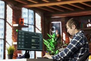 Man seated at desk speaking with AI LLM chatbot software in modern home office. Person communicating with large language model program on computer in bright apartment room photo