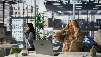 Sleepy overworked female employee yawning at her office desk, feeling exhausted with her work and suffers burnout. Businesswoman dealing with fatigue and low energy, challenges at job. Camera B. photo