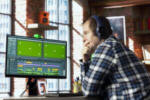 editor analyzing film montage on green screen computer monitor before editing color grading and lighting in home office. Post production studio employee working with raw footage on chroma key PC photo