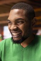 Joyful man watching comical videos on social media at home and laughing. Upbeat african american person using social network website, amused by funny memes, slacking off in apartment photo