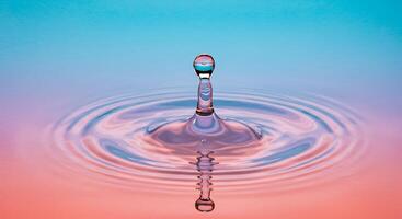 A drop of water is falling into a blue and pink colored water photo