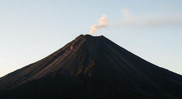A volcano is seen from above with smoke coming out photo