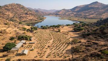 Remote African Village with Farm Fields and Lake Below Mountains. photo