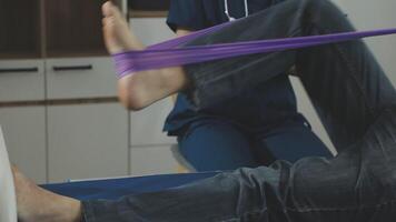 A man is sitting on a bed with a purple band around his leg video
