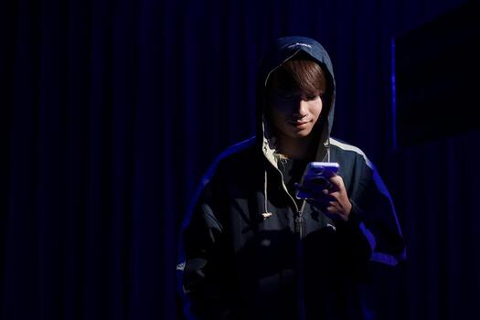 Young man hacker using smartphone for phishing attack and data theft in dark cyber environment photo