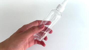 hand with minimalist manicure holding transparent bottle with small amount of water and narrow spout video