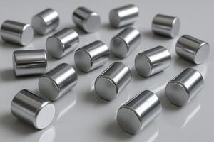 Metallic cylindrical objects scattered on a reflective gray surface, close up view photo