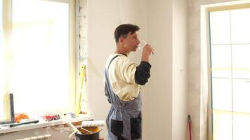 Construction worker taking a well-deserved break from renovating an apartment, enjoying a refreshing glass of water in a partially finished room filled with tools and equipment video