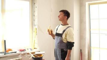 A man in overalls standing in a room with a banana video