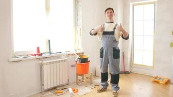 Professional painter showing thumbs up gesture, satisfied with the progress of a home renovation project, surrounded by painting tools and equipment video