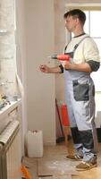 A man in overalls is holding a drill video