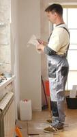 A man in overalls is standing in a room with a wall video