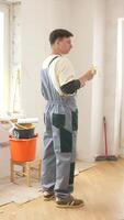 A man in overalls standing in a room with a paintbrush video