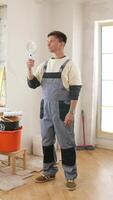 A man in overalls standing in a room with a magnifying glass video