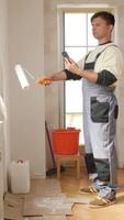 A man in overalls is holding a paint roller video