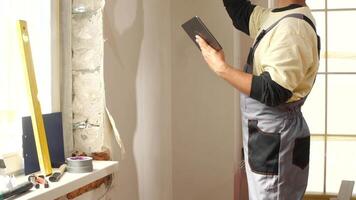 A man is standing in front of a window with a tablet video