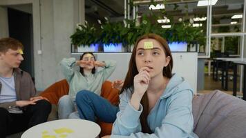 Teenagers playing guessing game with sticky notes on foreheads video