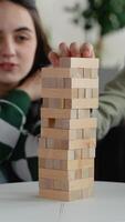 Teenage carefully playing jenga blocks on white table video
