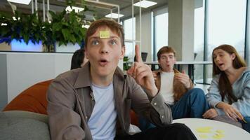 Teenagers playing guessing game with sticky notes on foreheads video