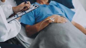 A doctor is writing on a clipboard while a patient is laying in bed video