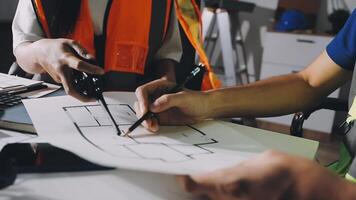 Two people working on a blueprint with a construction worker video