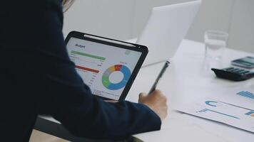 A businesswoman is using a tablet to view financial data video