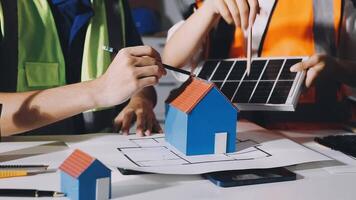 Two people working on a model house with solar panels video